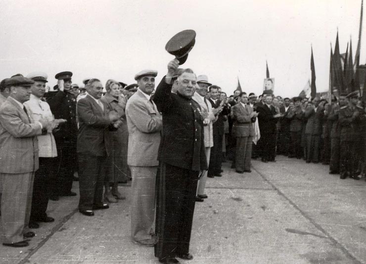 Mareşalul K.E. Vorosilov răspunzând ovaţiilor entuziaste ale mulţimii venită pe aeroportul Băneasa pentru a saluta plecarea delegaţiei guvernamentale sovietice, care a vizitat ţara noastră cu prilejul sărbătoririi zilei de 23 august 1951. Se aflau de faţă: Gheorghe Gheorghiu –Dej, Petru Groza, Chivu Stoica, Kavtaradze S.I., Vasile Luca, Teohari Gerogescu, Ana Pauker, Al. Leuconis, ş.a.     (25.08.1951).